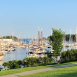 A photo of Camden Harbor showing green lawn and colorful boats